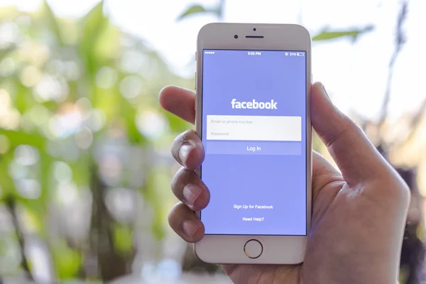 CHIANG MAI, THAILAND - JANUARY 02, 2015: A man trying to log in Facebook application using Apple iPhone 6. Facebook is largest and most popular social networking site in the world.