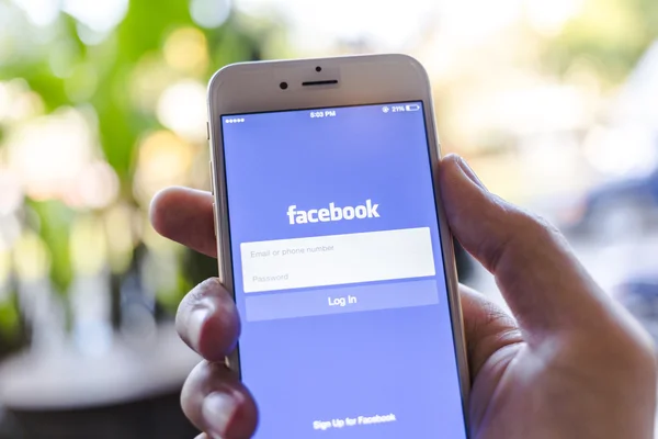 CHIANG MAI, THAILAND - JANUARY 02, 2015: A man trying to log in Facebook application using Apple iPhone 6. Facebook is largest and most popular social networking site in the world.