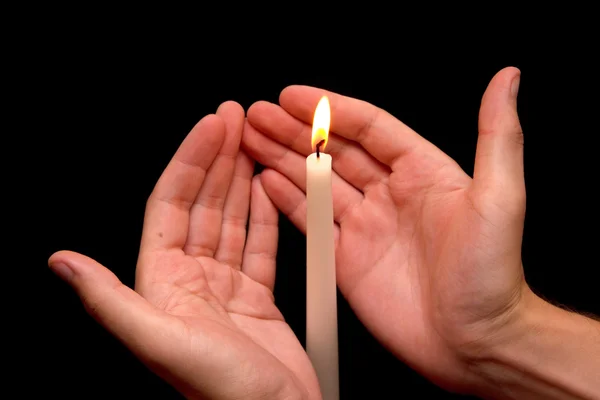 Hands holding a burning candle in dark