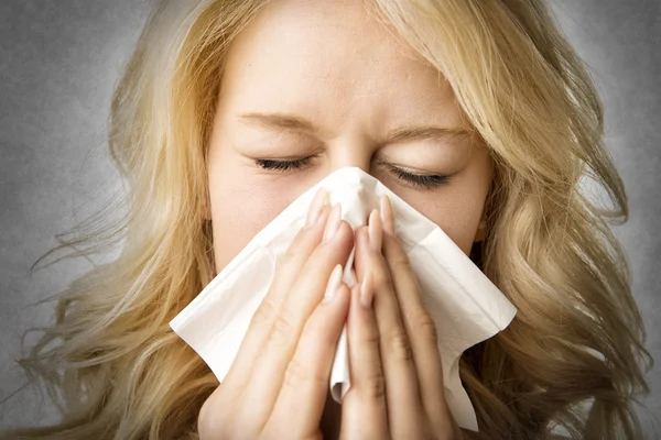 Ill woman with tissue is sneezing