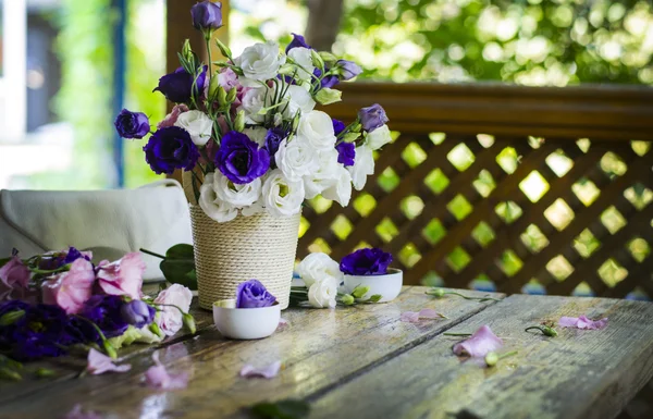 Beautiful bunch of white and purple roses in a vase on a wooden table.