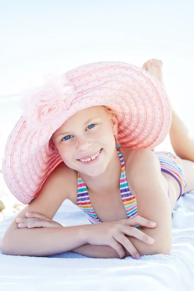 Happy cute child lying down on deckchair of beach resort for summer holidays or travel vacations