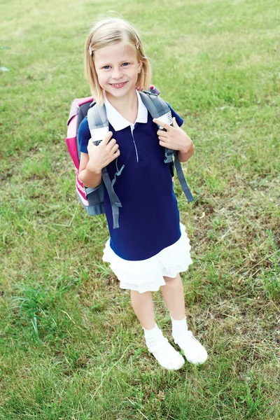 Portrait of a smiling schoolgirl in a blue school dress.