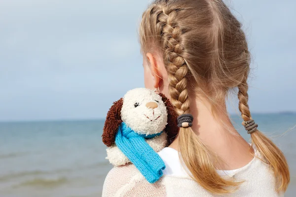 Children psychology. The little beautiful girl embraces an amusing  dog - toy. Favorite soft toy.