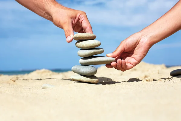 Man and woman together to build a tower made of stones.