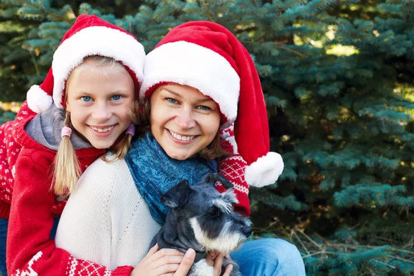 Happy family with dog near a Christmas tree on the street