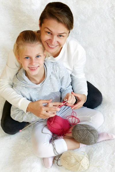 Mom teaches a child to knit.