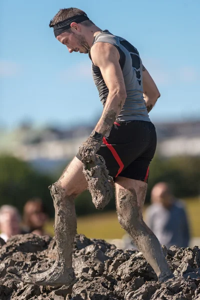 Man with shoes in hand at the Mud Charge by Backstrom at the Tou