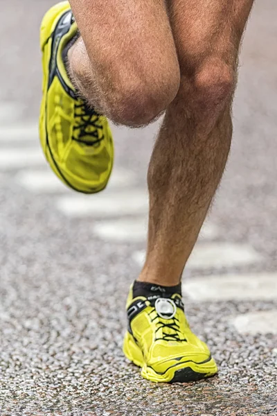 Closeup of a runners legs with colorful yellow shoes at the wet