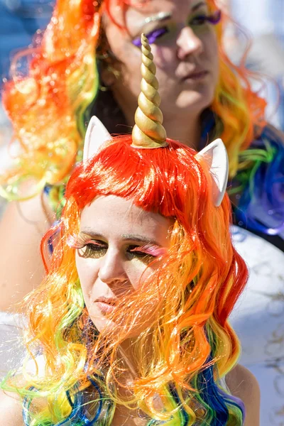Girl in long rainbow hair and unicorn costume at the Pride parad