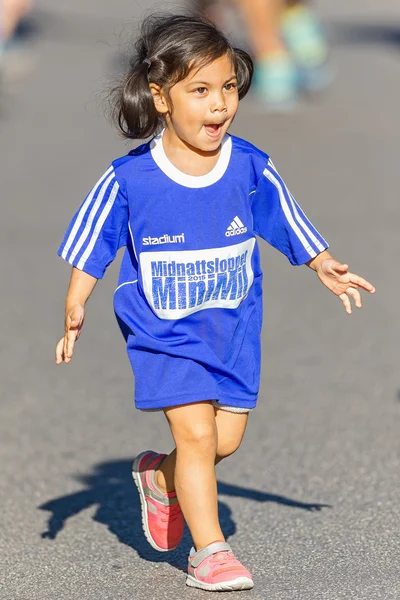 Young girl with big blue shirt running the Minimil for the young