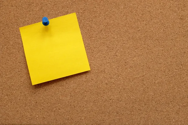 Yellow note paper pinned to a cork board