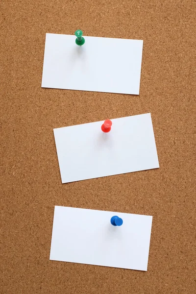Three blank cards pinned to a cork board
