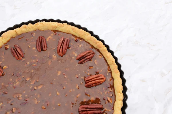 Pecan nuts decorating the top of an unbaked pecan pie