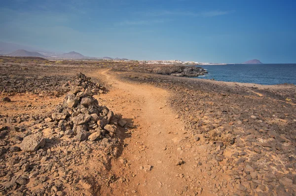 Path in scenic volcanic landscape bordered by coastline in south Tenerife island, Canary islands, Spain.
