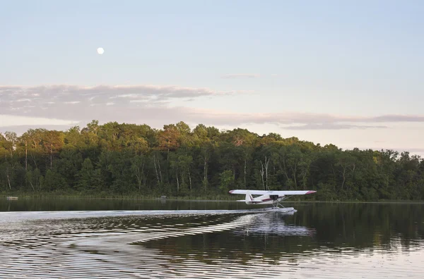Small floatplane taxis for takeoff on calm Minnesota lake