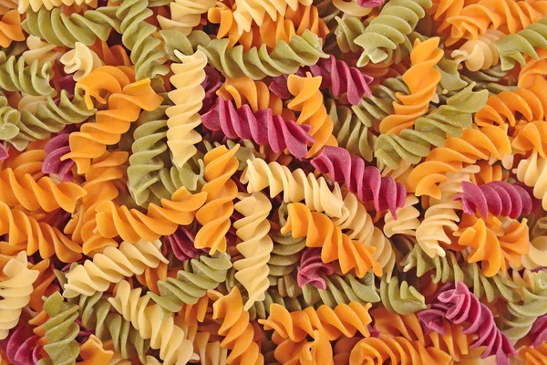 Colored uncooked italian pasta fusilli as background