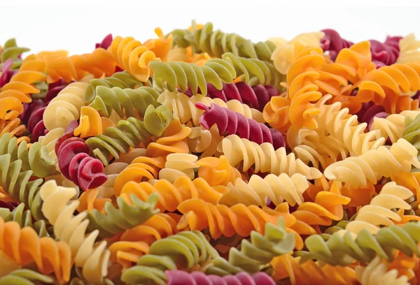 Heap of colored uncooked italian pasta fusilli on a white