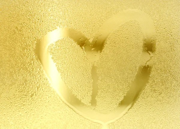 Golden heart shape color, water drop on glass. Illuminate background.