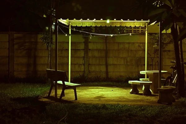 Bench under lamp In home garden during the night