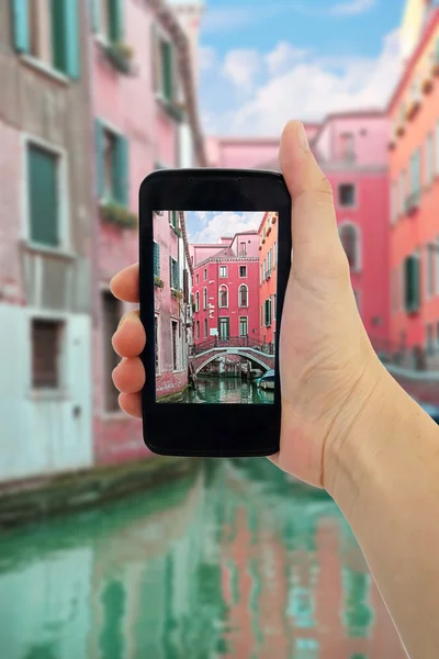 Travel concept - tourist taking photo of canal, gondola, boats in Venice, Italy on mobile gadget