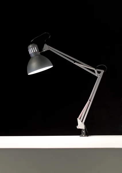 Adjustable desk lamp over black background