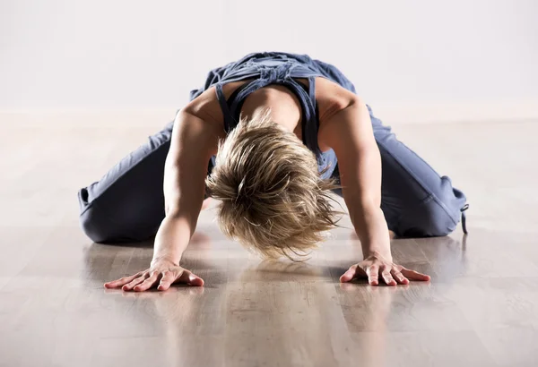 Woman with head down while stretching hip muscles