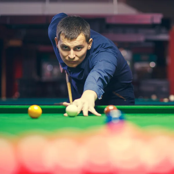 Young man lines up his shot as he breaks the balls for  start  game of billiards