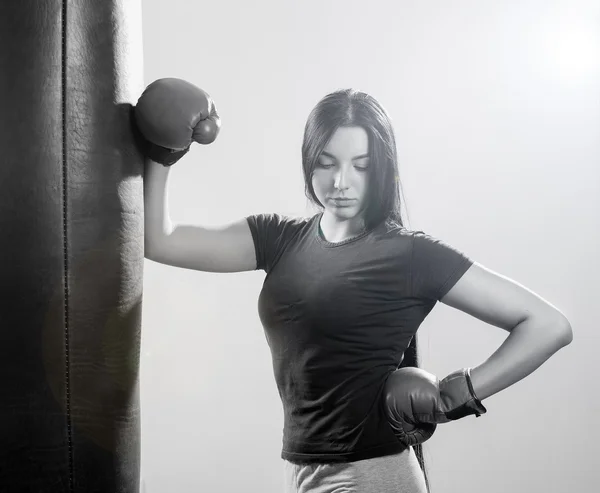 Brunette woman in boxing gloves and body hitting pear.