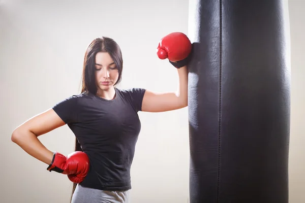 Sports girl in boxing gloves and body punching bag