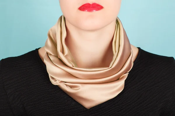 Silk scarf. Beige silk scarf around her neck isolated on blue background.