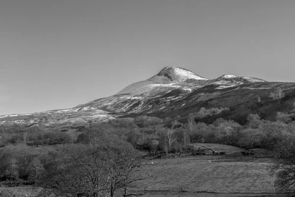 Black and white long view of a snow capped mountain