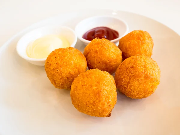 Deep fried cheese balls with sauce on white background