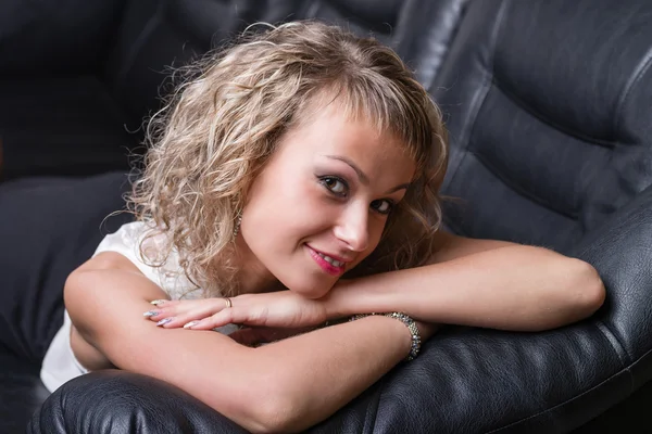 Very beautiful, sensual sexy blonde girl lying on a balck sofa