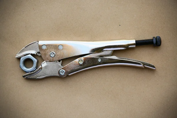 Close up locking pliers on wooden background, Hand tools in work shop.