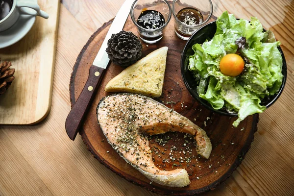 Salmon steak on wooden table in restaurant, Fresh steak for healthy food and clean food or fresh food for diet, International steak on plate with fresh vegetable or salad in the restaurant.