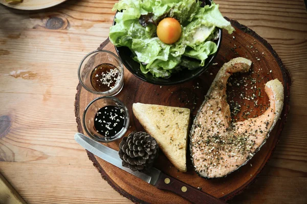 Salmon steak on wooden table in restaurant, Fresh steak for healthy food and clean food or fresh food for diet, International steak on plate with fresh vegetable or salad in the restaurant.
