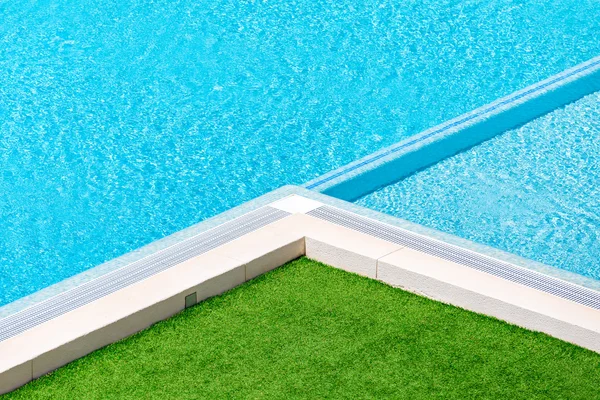 Corner of swimming pool with green grass around