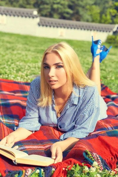 Beautiful smiling woman reading book in park