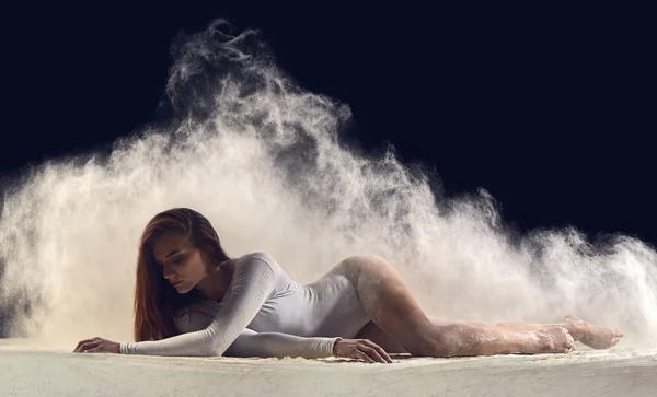 Dancer posing gracefully on the floor in a cloud of dust