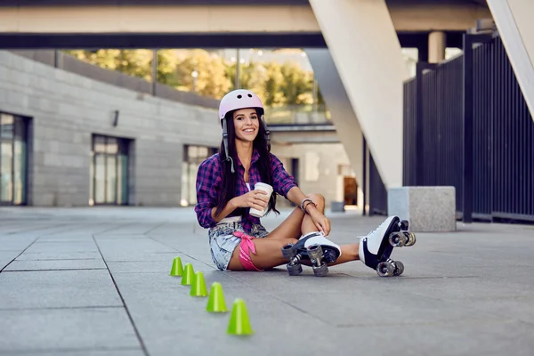 Young woman take a rest after riding roller skates and drinking coffee