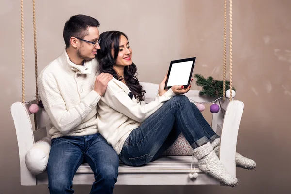 Happy young couple with a tablet computer on swing
