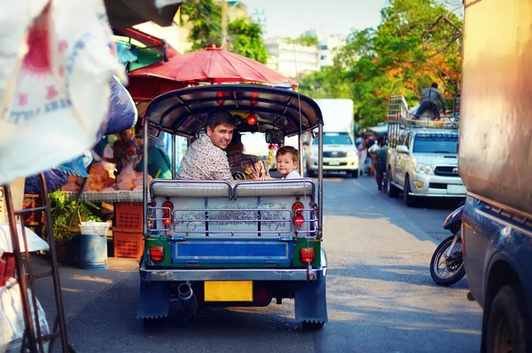 Happy tourist family travel through the asian city on tuk-tuk taxi