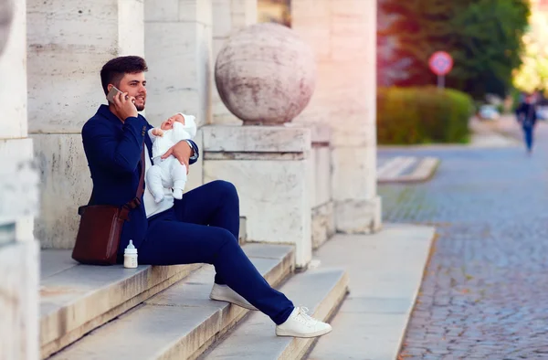 Happy young father busy with work with his newborn son