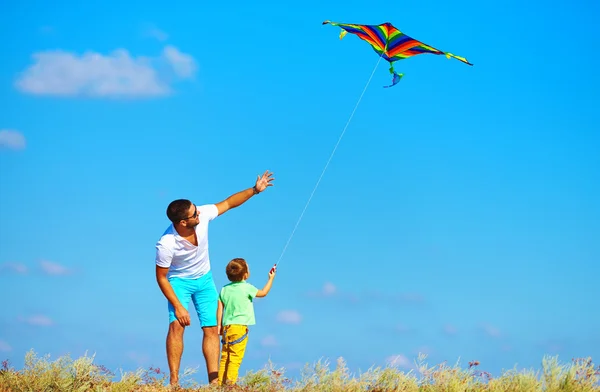 Father and son having fun, playing with kite together