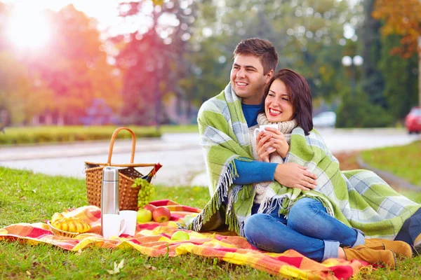 Happy couple enjoying autumn picnic in city park