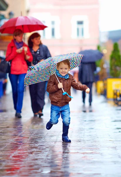 Happy boy running through rainy city street