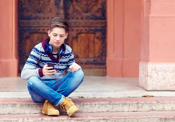 Stylish teenage boy listens to the music on smart phone