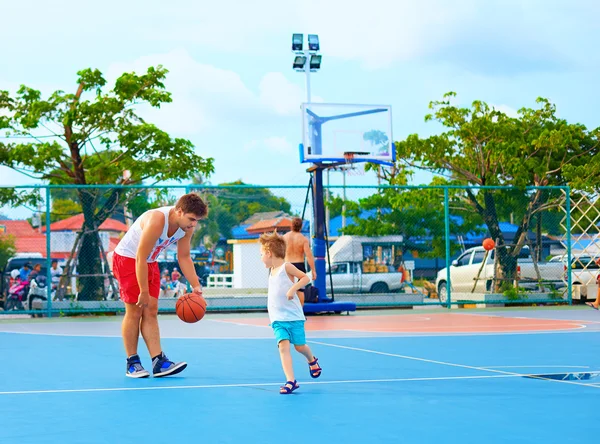 Father and son playing basketball on sport ground