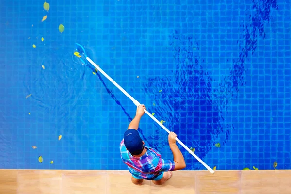 Young adult man, personnel cleaning the pool from leaves